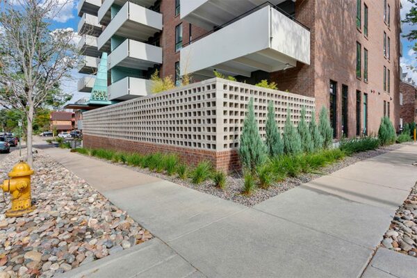 The Scot apartments with classic brick construction, large balconies, and lush rocky landscaping.