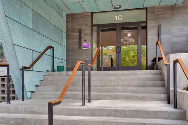 Entry to the Scot apartments with modern railings up concrete steps.