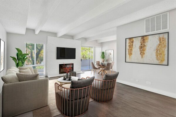 Living room with wood floor, brick accent wall with fireplace and mounted TV, and elegant furniture.