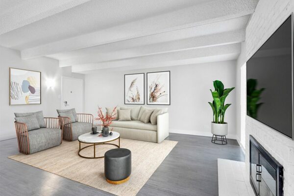 Living room with wood floor, plush rug, modern furniture, framed artwork, and brick accent wall.