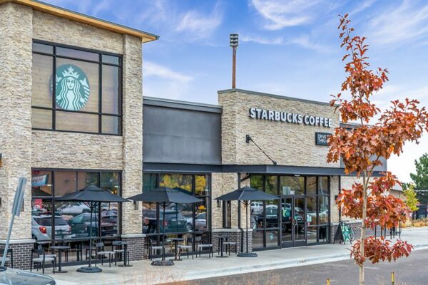 Starbucks Coffee storefront with glass doors and autumnal tree.