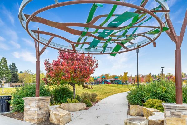 Wheat Ridge Discovery Park with lush landscaping, play equipment, and large sculpture.