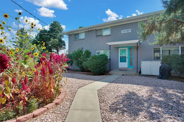 Trace Townhomes with rocky landscaping, grey brick construction, and concrete paths and patios.
