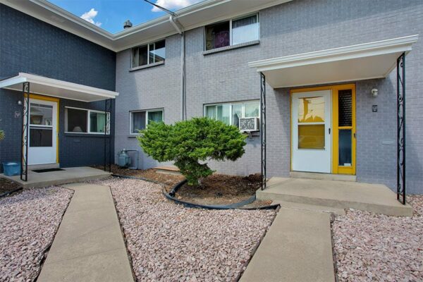 Trace Townhomes with concrete pathways and patios, rocky landscaping, and large shrub.