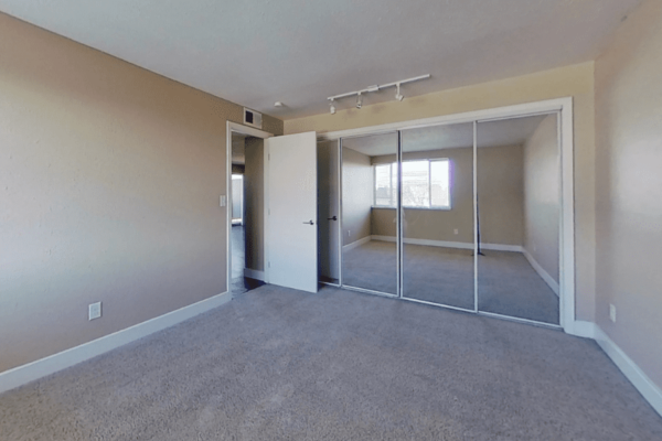 bedroom view with mirror closet and view of living room