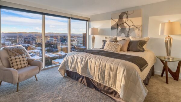 bedroom with bed, couch and large windows overlooking the city