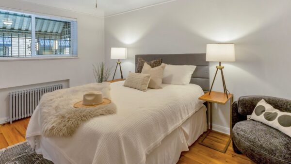 bedroom with bed in the middle, large window, and night stand
