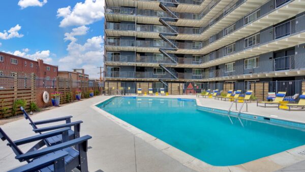 resort style pool with yellow lounge chairs and balconies in the background