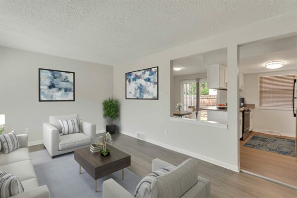 Living room with rug, couch, chairs and wall art.