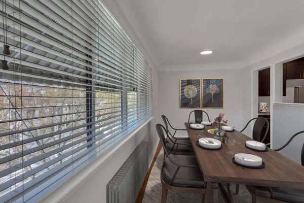 Dining room with white walls, artwork, and windows.