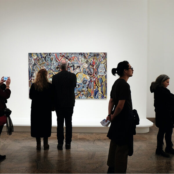 People in quiet art gallery looking at abstract art piece.