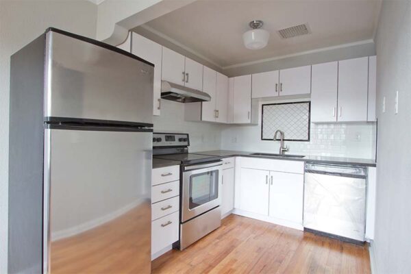 Kitchen with wood floors, white cabinets, and white tile backsplash.
