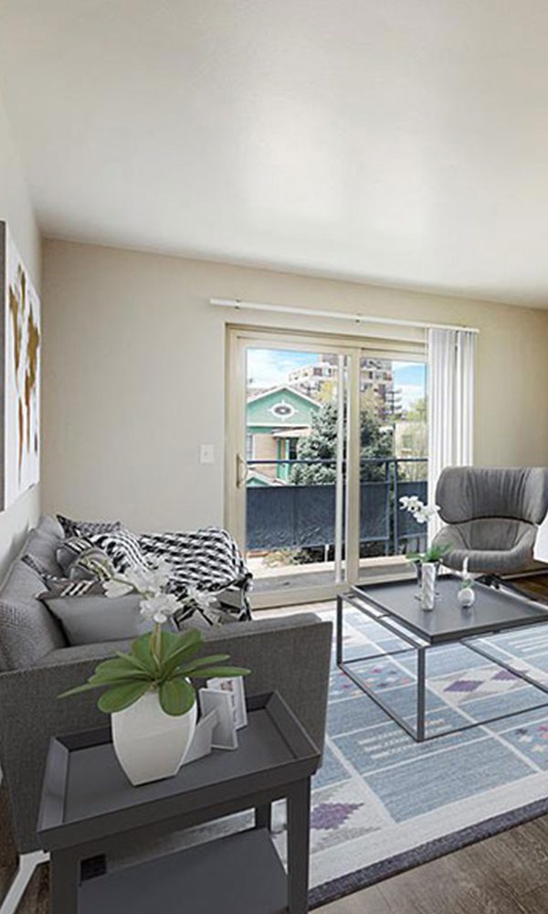 Living room with wood floor, rug, plush furniture, large window, and door to balcony.