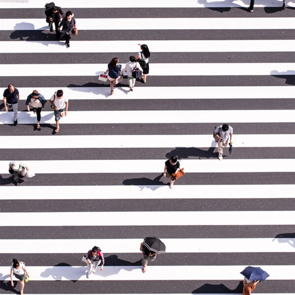 Overhead view of pedestrians crossing striped crosswalk.