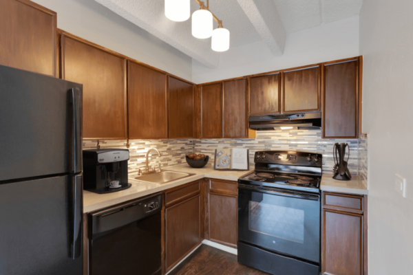 kitchen with dark wood cabinets, black appliances, and white tile back splash
