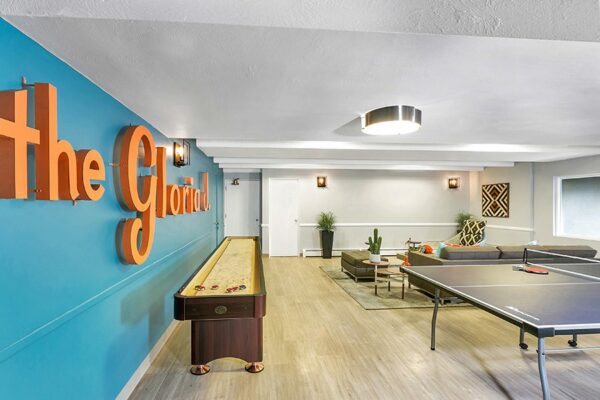 Club room with wood floor, table tennis, shuffleboard, and blue accent wall with 