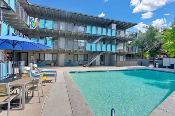 Pool area with lounge chairs and tables overlooked by apartment balconies.