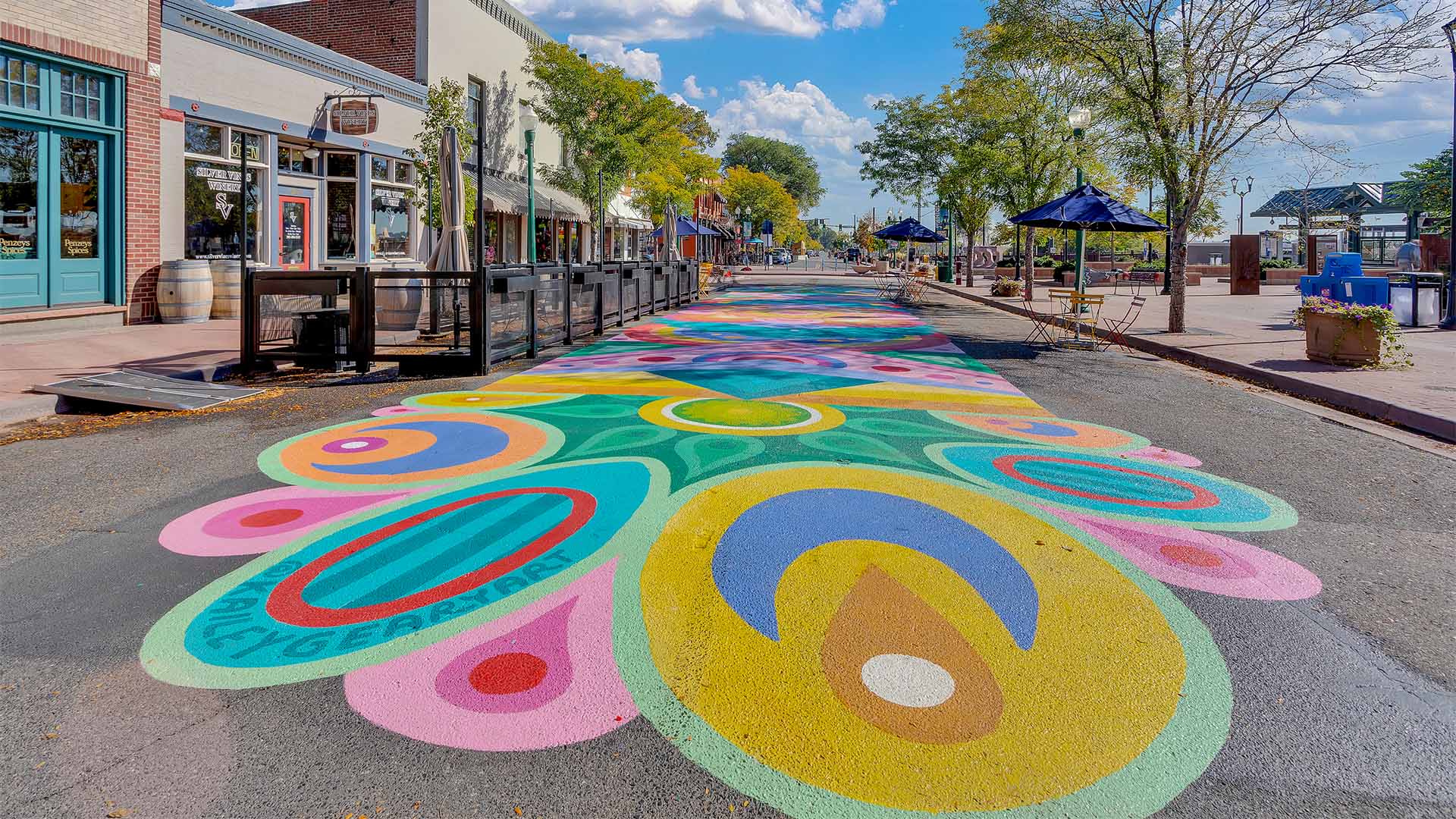 Old Town Arvada street with storefronts and colorful street art.