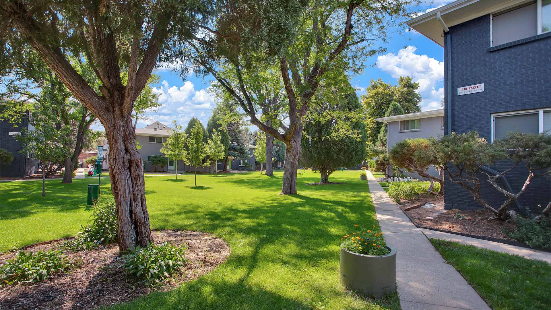 Trace Townhomes with lush lawns, mature trees, and concrete pathways.