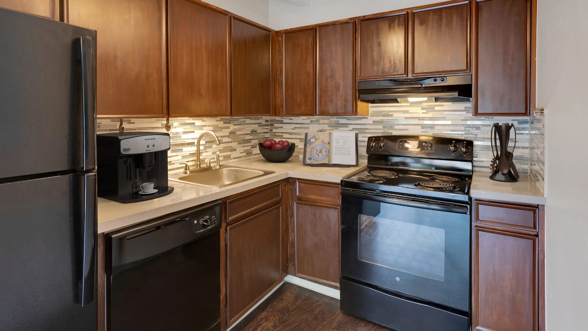 kitchen with dark wood cabinets and white tile back splash and black appliances