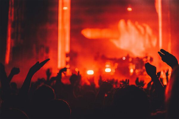 People dancing at concert with brightly lit red stage.