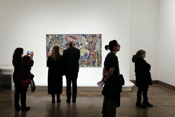People in quiet art gallery looking at abstract art piece.