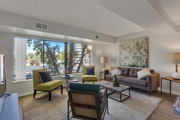 Furnished living room with white walls, large windows, and artwork on the walls.