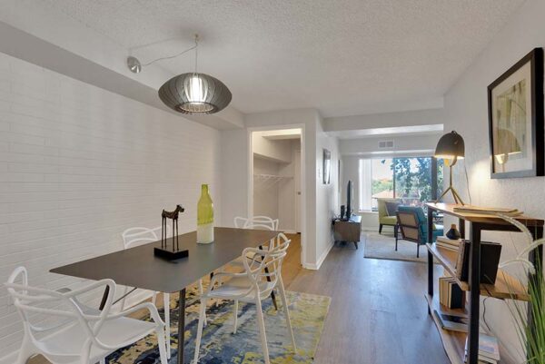 Furnished dining room with a carpet under the dining table, white walls, and wood floors.