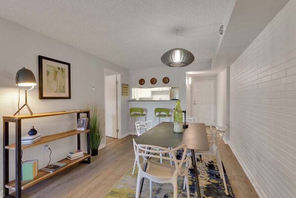 Furnished dining room with a carpet under the dining table, white walls, and wood floors.