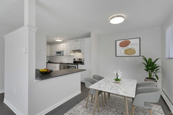 Rendering of a kitchen and dining room with gray floors, white walls, and white cabinets.