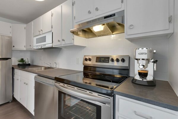 Rendering of a kitchen with wood floors, white cabinets, and gray countertops.