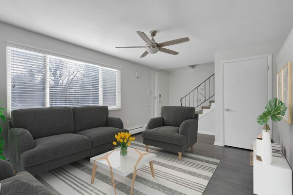 Rendering of a furnished living room with white walls, gray floors, and a carpet underneath the couch and chairs.