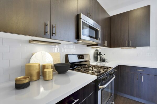 Rendering of a kitchen with wood floors, dark wood cabinets, and white countertops.