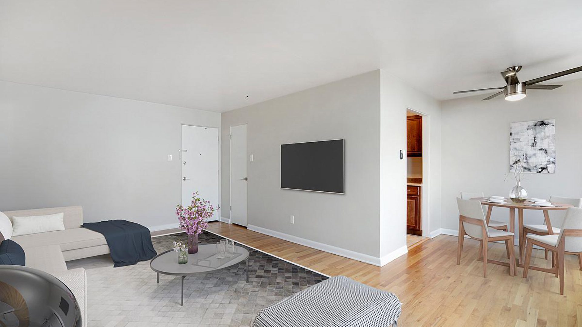Living room with wood floor, modern furniture, ceiling fan, and door to kitchen.