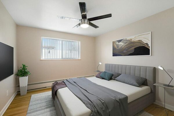 Bedroom with wood floor, rug, plush bed, modern bedside tables with lamps, and ceiling fan.