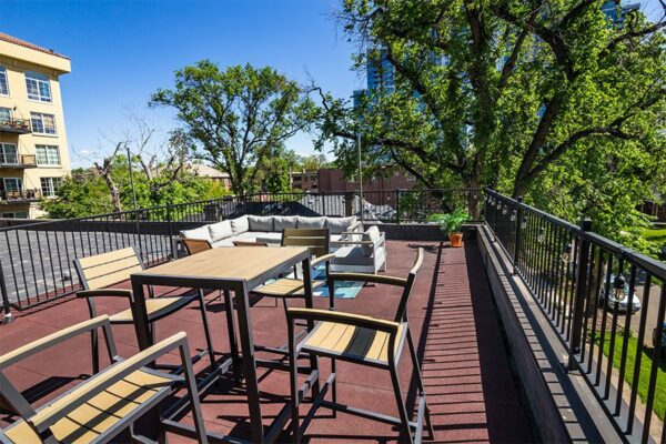 Rooftop patio with plush outdoor furniture, railings with string lights, and large plants.