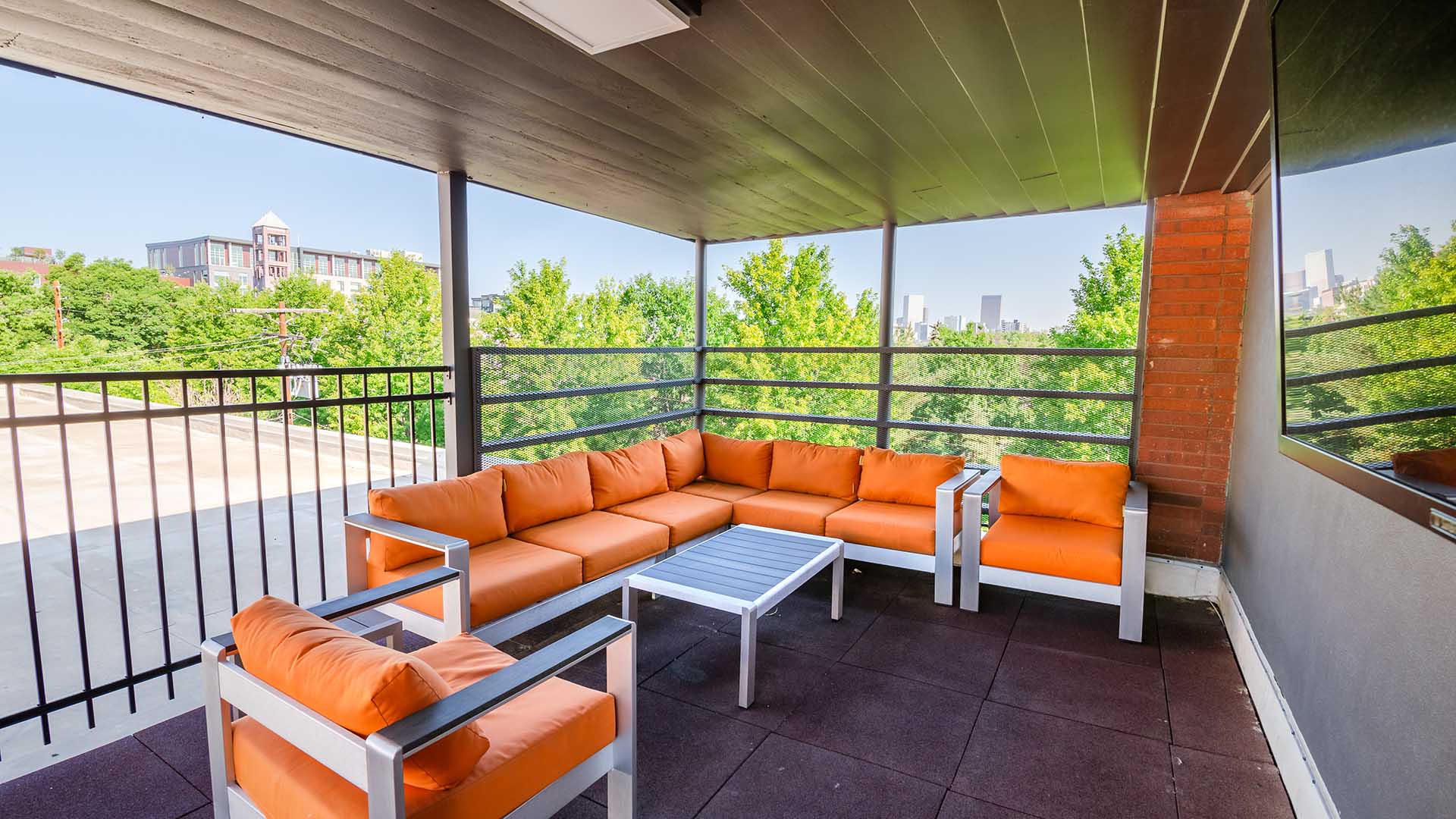 Rooftop patio with plush orange outdoor seats and TV.