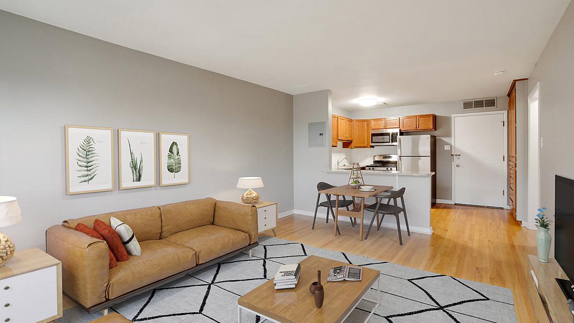 Living room with geometric rug, leather couch, modern furniture, dining table, and kitchen.