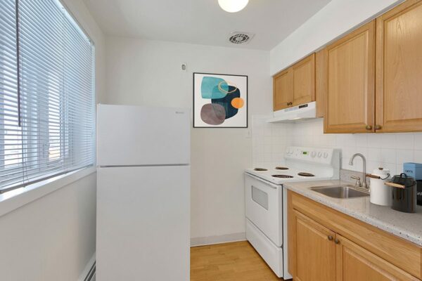 Kitchen with wood cabinets, white countertops, and white appliances.