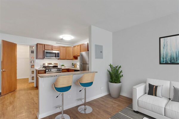 Living room and kitchen with updated appliances, plush seating, and breakfast bar.