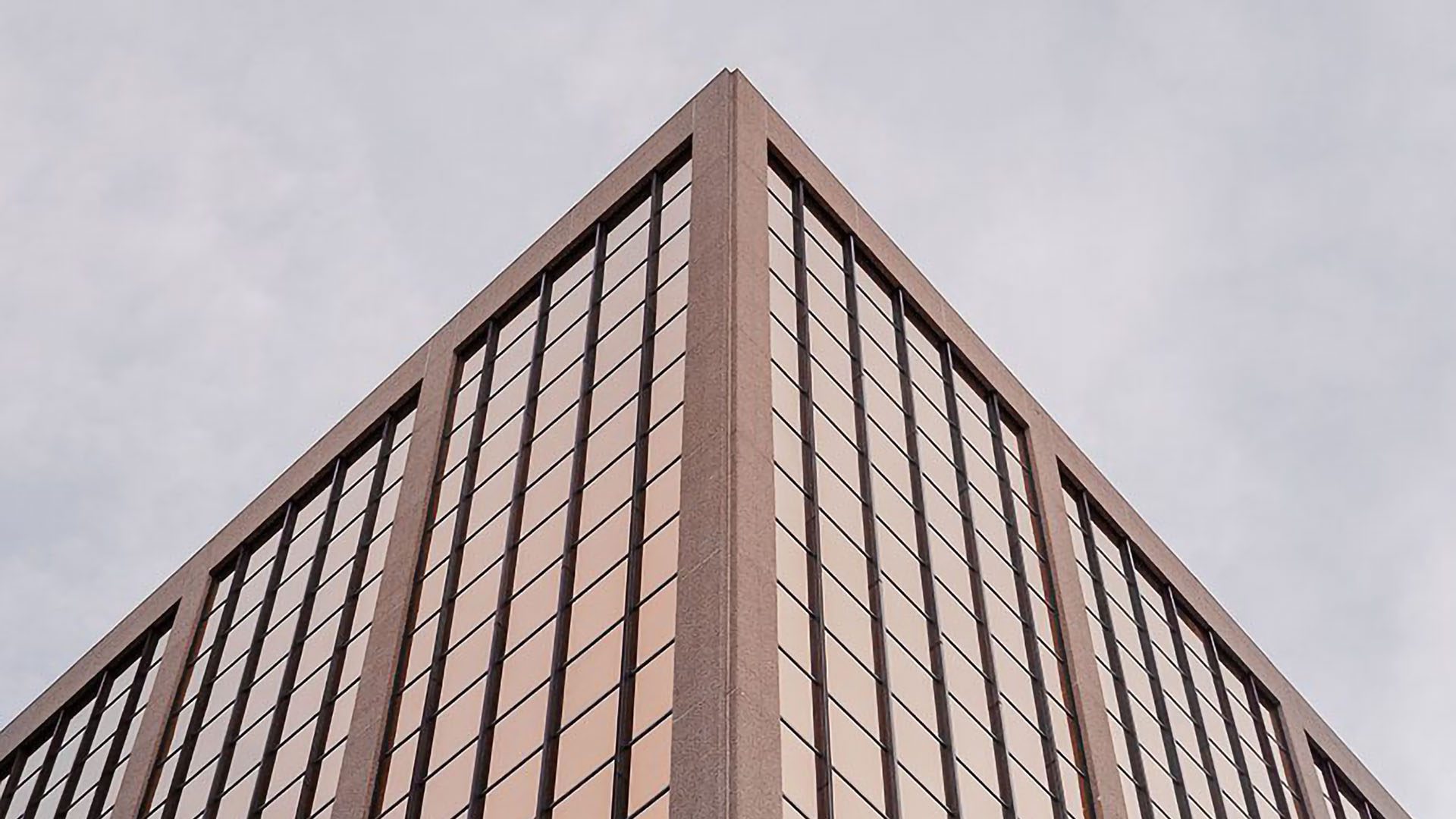 Symmetrical image of office tower with rose gold reflective windows.