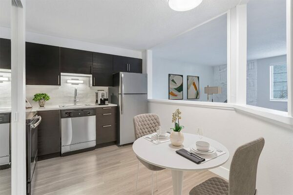 Kitchen with dark wood cabinets, stainless steel appliances, and wood floors with a dining table.