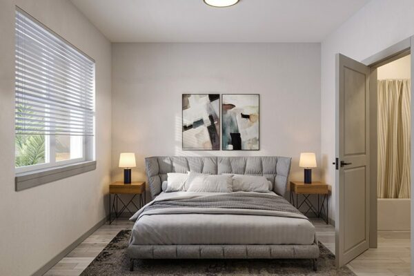 Bedroom with plush bed, bedside tables with lamps, large window, and door to bathroom.