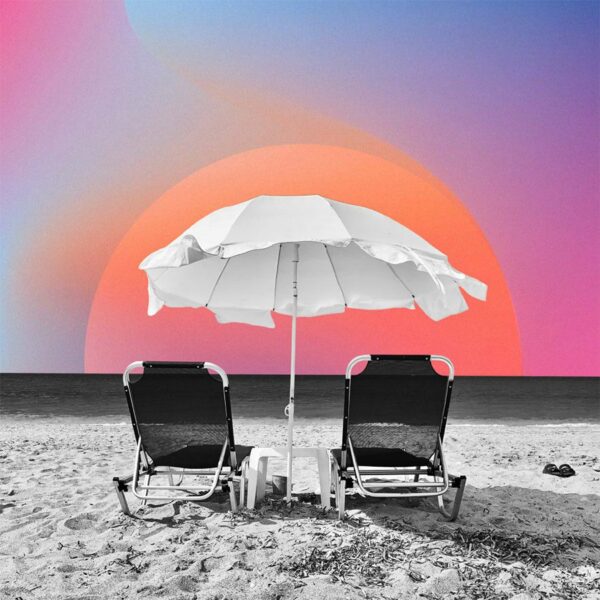 Lounge chairs and umbrella on beach in front of colorful gradient sky.