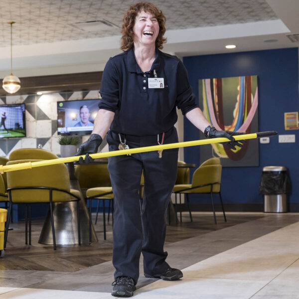 Image of woman holding a mop in a maintenance uniform