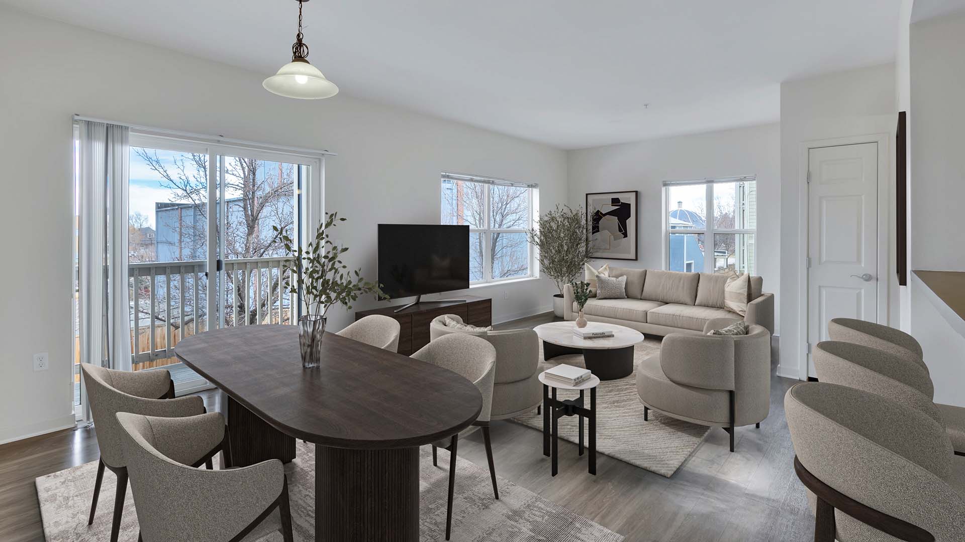 Trocadero apartment living room with plush seating, console with TV, dining table, and balcony door.
