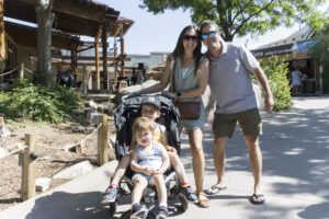 family of 4 posing for photo with two kids in stroller