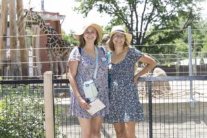 two women posing with giraffes