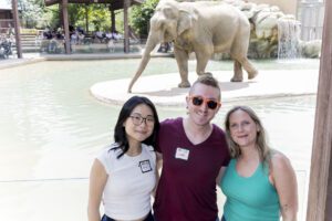 three friends posing with elephant at the zoo